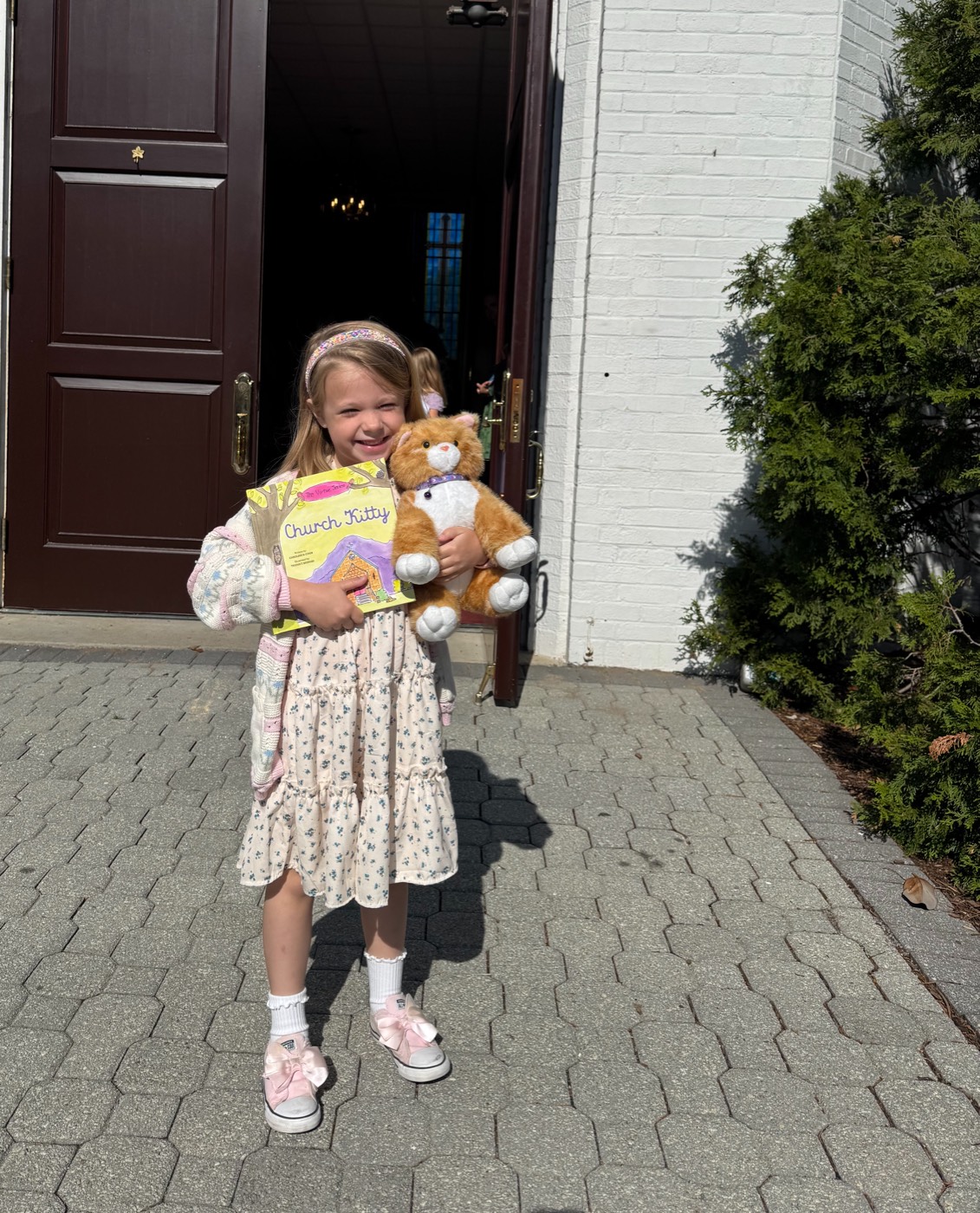 A young girl outside church holding the Church Kitty book and plush